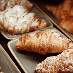 Close-up of freshly baked croissants dusted with powdered sugar in a Sardinian cafe.